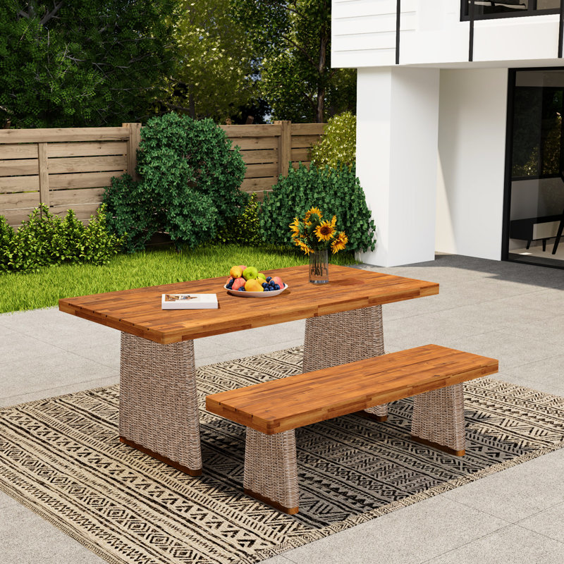 Ensemble de table et de banc d'extérieur en bois brun, structure à lattes pour le drainage, pieds tressés à la main, résistant aux intempéries. Sa conception robuste assure une grande stabilité.