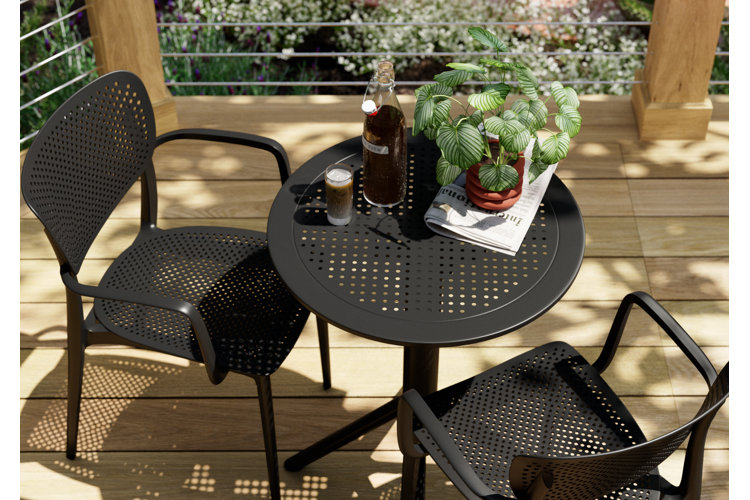metal outdoor patio dining set on a deck with a potted plant, cold brew, and a newspaper
