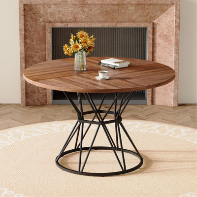 Une table de salle à manger circulaire d'un diamètre de 47,3 pouces, comprenant 4 plateaux de table en bois aggloméré à grain de bois de noyer, des supports en métal en forme de sablier noir et une table de salle à manger de style industriel moderne pour 4 à 6 personnes.