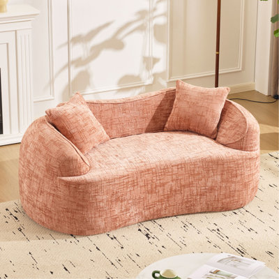 Pink curved two - person compress sofa. It has armrests on both sides, comes with two pillows, is suitable for small - sized apartments, and can be placed in the living room or bedroom.