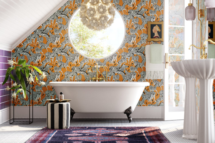Claw-foot bathtub up against a wall with a circular window and zebra wallpaper and directly beneath a flower-shaped chandelier.