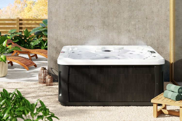 backyard with a hot tub, wooden lounge chairs, and tropical lanscaping