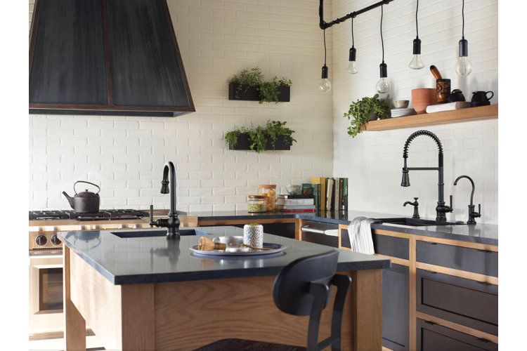industrial kitchen with a black center island and black countertop sink with wood shelves above. two black faucets and a black range hood