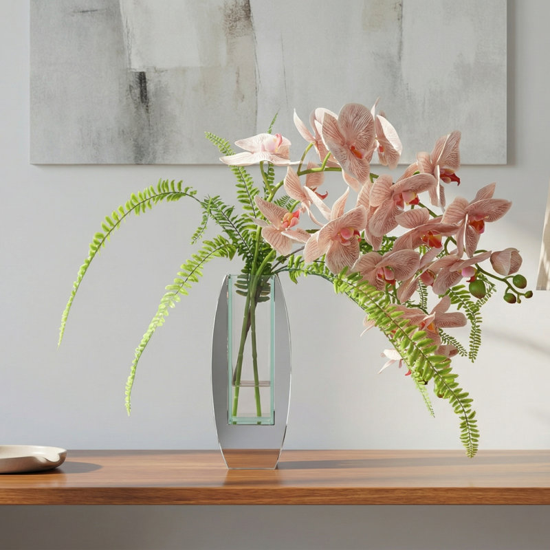 Orchidées et fougères disposées dans un vase miroir en verre avec fougères