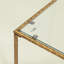 Table basse Kyea moderne avec dessus en verre et structure en laiton antique