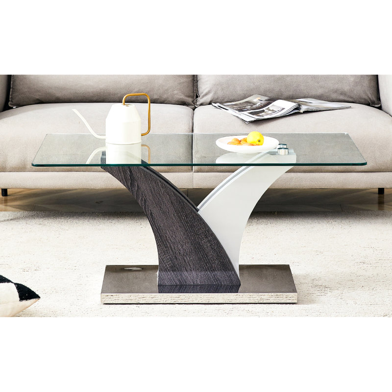 Table basse rectangulaire en verre avec pattes stables et design artistique dans les tons gris et blanc. Élégant plateau transparent.