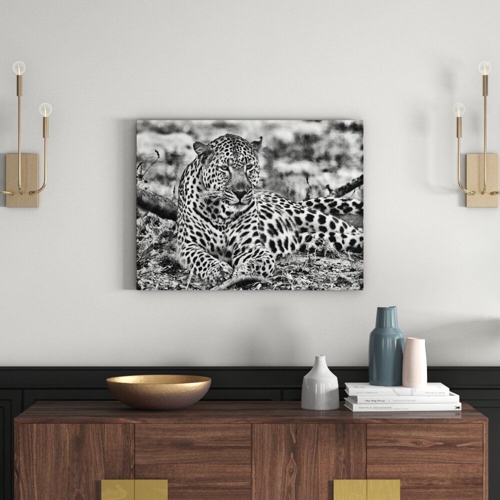 Leinwandbild Liegender Leopard im Laub in Monochrom