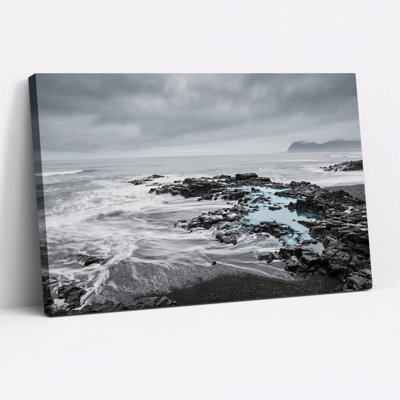 Tableau sur toile représentant un rivage rocheux en noir et blanc avec une eau bleue