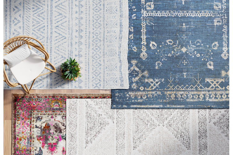 Four area rugs overlapping each other and displayed to showcase different rug colors and patterns.