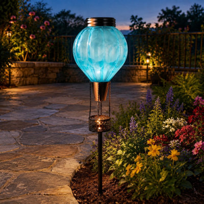 A Blue hot-air-balloon solar garden stake light combines waterproof construction with flickering lantern light for lawn, pathway, or patio decor. For outdoor use.