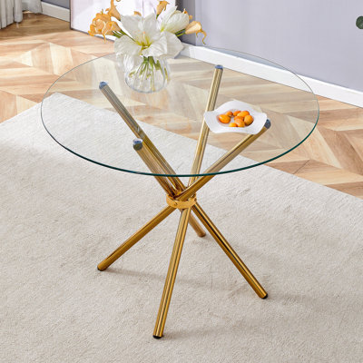 Table de salle à manger ronde en verre transparent avec une forme unique pour 4 à 6 personnes, avec des pieds en métal doré rassemblés en forme d'anneau