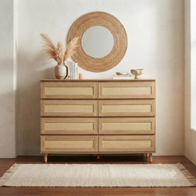 Commode moderne à 8 tiroirs pour chambre à coucher, aspect bois naturel, en MDF avec façades de tiroirs en rotin, pieds surélevés, grand espace de rangement et large plateau pour une entrée bien organisée.