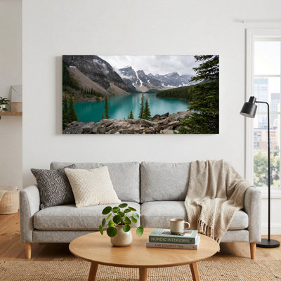 Tableau sur toile représentant un lac de montagne turquoise avec des sommets enneigés et des pins