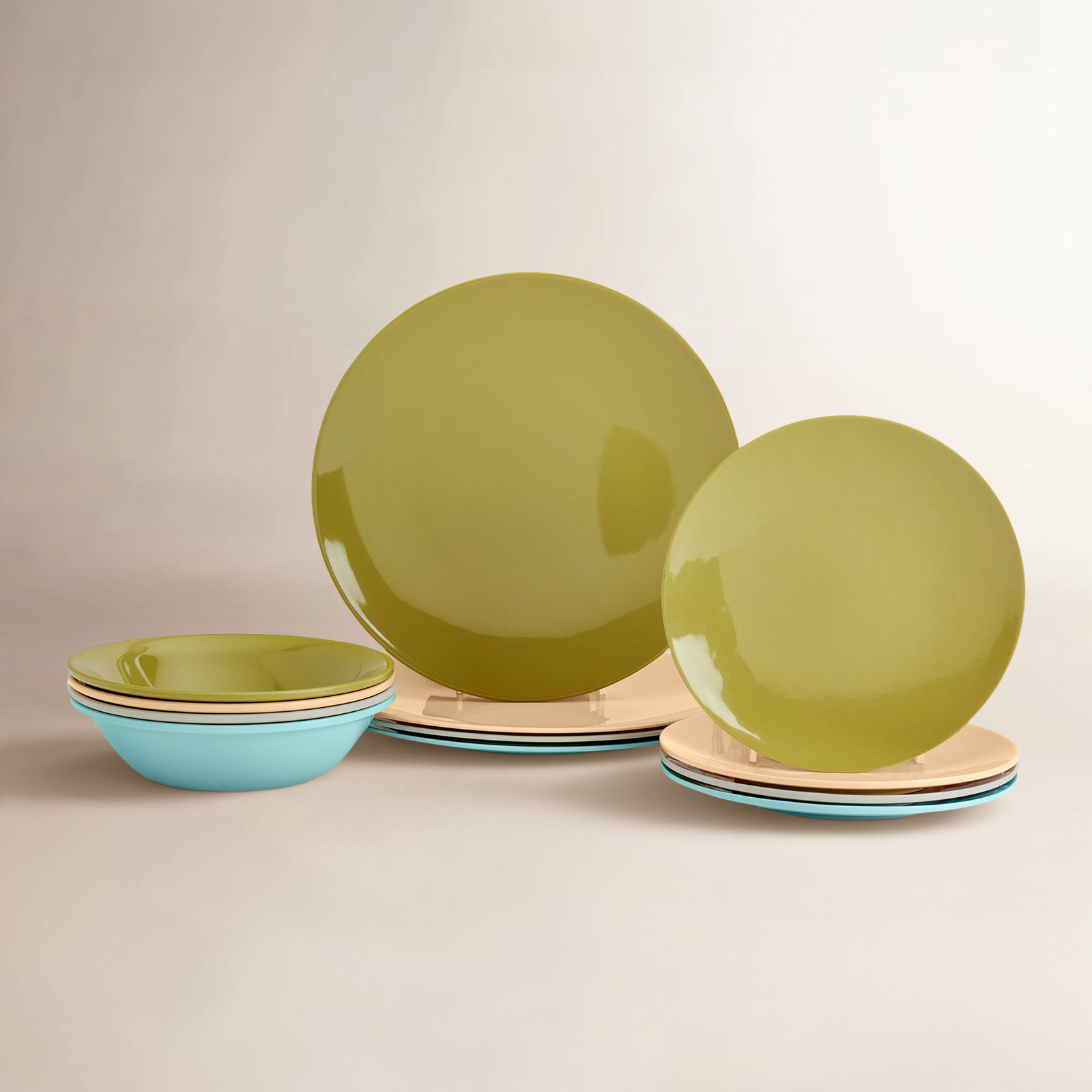 Dinnerware set including olive green plates, tan plates, and light blue bowls in a stackable, multicolored design.