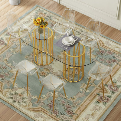 Ensemble de table et de chaises Table de salle à manger ovale en verre trempé de 71 pouces de style luxueux à double colonne dorée. Jumelé avec 6 chaises en plastique transparent avec des pieds en métal doré.