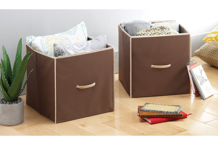 two brown storage cubes with pillows and blankets in them