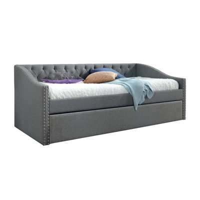 Lit de jour moderne capitonné avec couchette coulissante et garniture cloutée pour des solutions de couchage et de sièges polyvalentes.