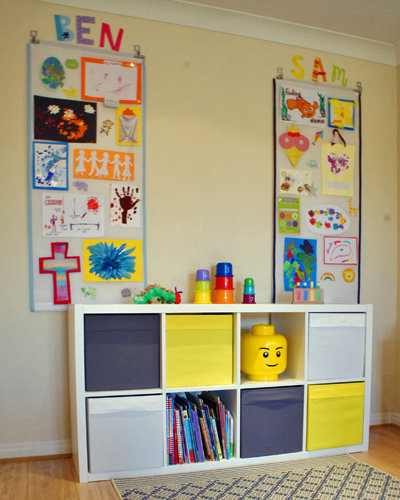 two roller blinds hung up on the wall and covered in children's art