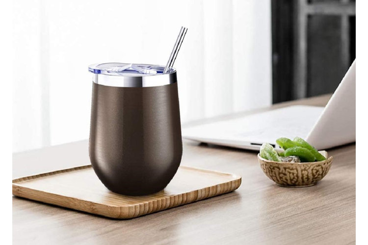 brown, stainless steel 12 oz. tumbler with a clear plastic lid and straw resting on a wood table