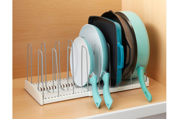 A kitchen cabinet with a horizontal kitchenware divider used to store different sized pans and skillets on their side.