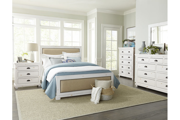 coastal-style bedroom with pale blue and white bedding and a woven rug