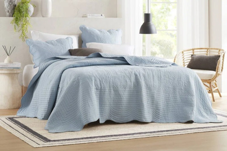 wooden platform bed with a blue scalloped-edge bedspread and matching pillow shams in a modern bedroom