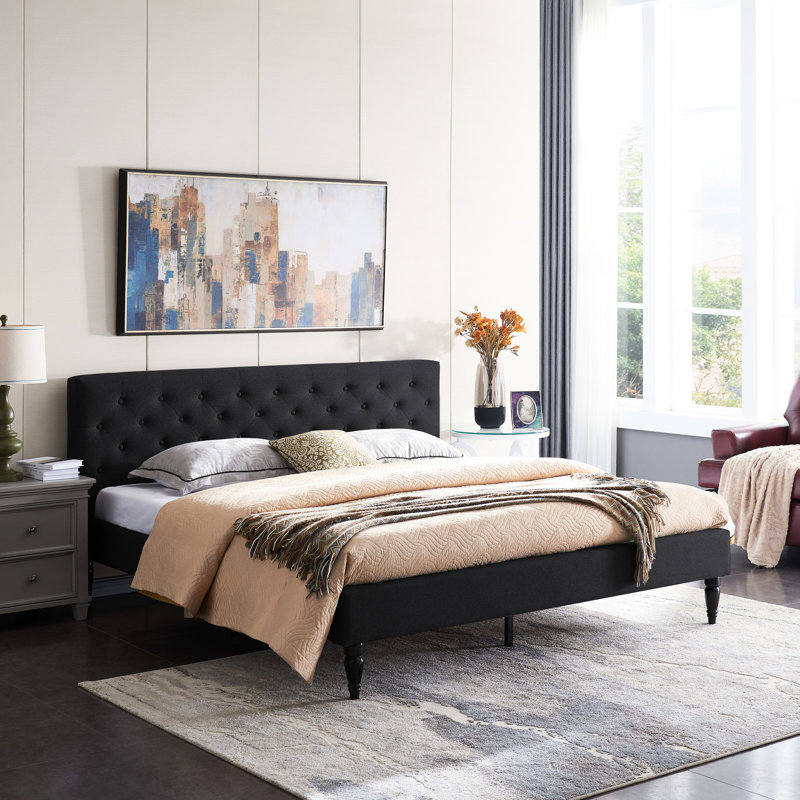 Très grand lit tapissier avec coutures à losanges, profil bas, lattes en fer, noir, pieds en bois franc touffetés, solide