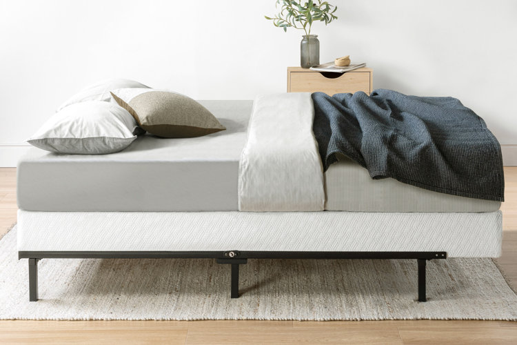 metal bed frame with a box spring, mattress, and neutral bedding