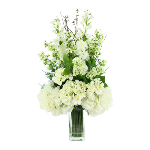 Arrangement floral Delphinium, hortensia et fougère dans un grand vase en verre