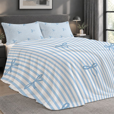 Ensemble de 3 pièces comprenant une couverture légère en flanelle de qualité supérieure et 2 taies d'oreiller à rayures bleues et délicats nœuds bleu clair. Ultra-doux et chaud, cet ensemble de literie est idéal en toute saison. Dimensions : 152 x 203 cm. La couverture est anti-boulochage et lavable à la machine.