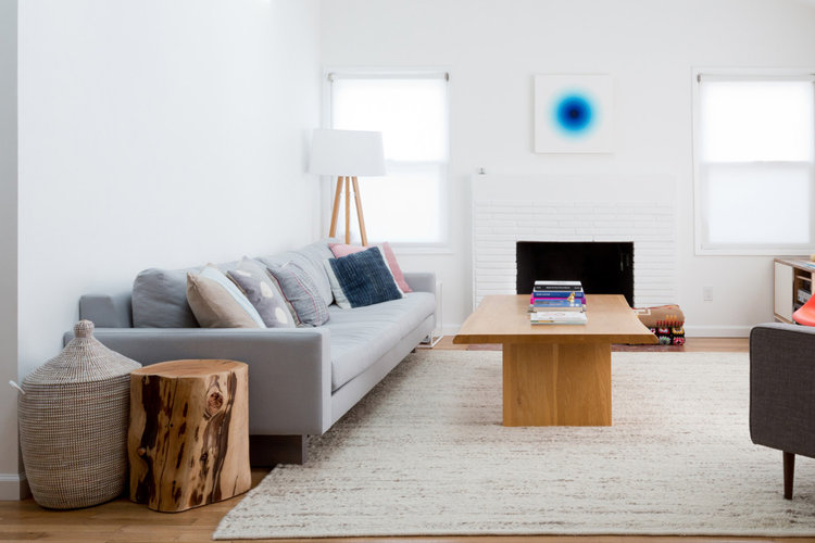 A streamlined white living room with wood accents and a woven storage basket.