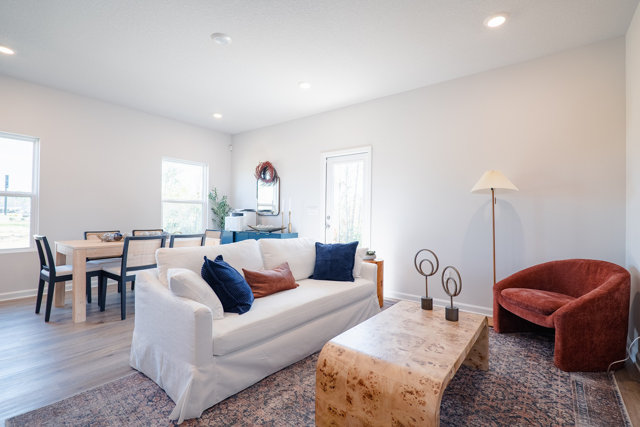 Living room with white couch, wood-look coffee table, and rust-colored chair.