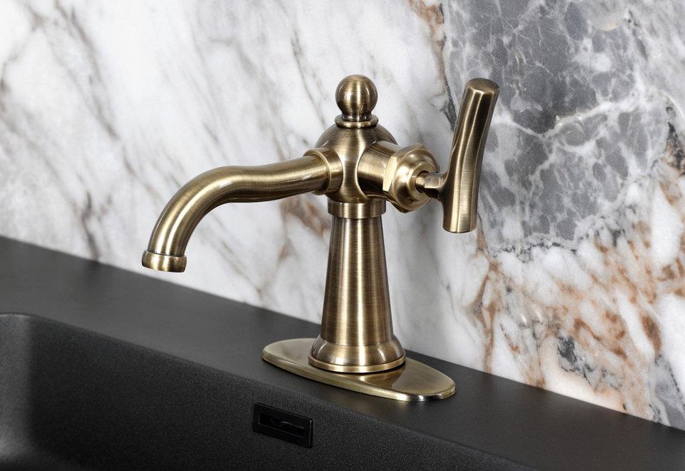 Single-handle kitchen faucet in an antique brass finish mounted on a black kitchen sink against a white marble backsplash.