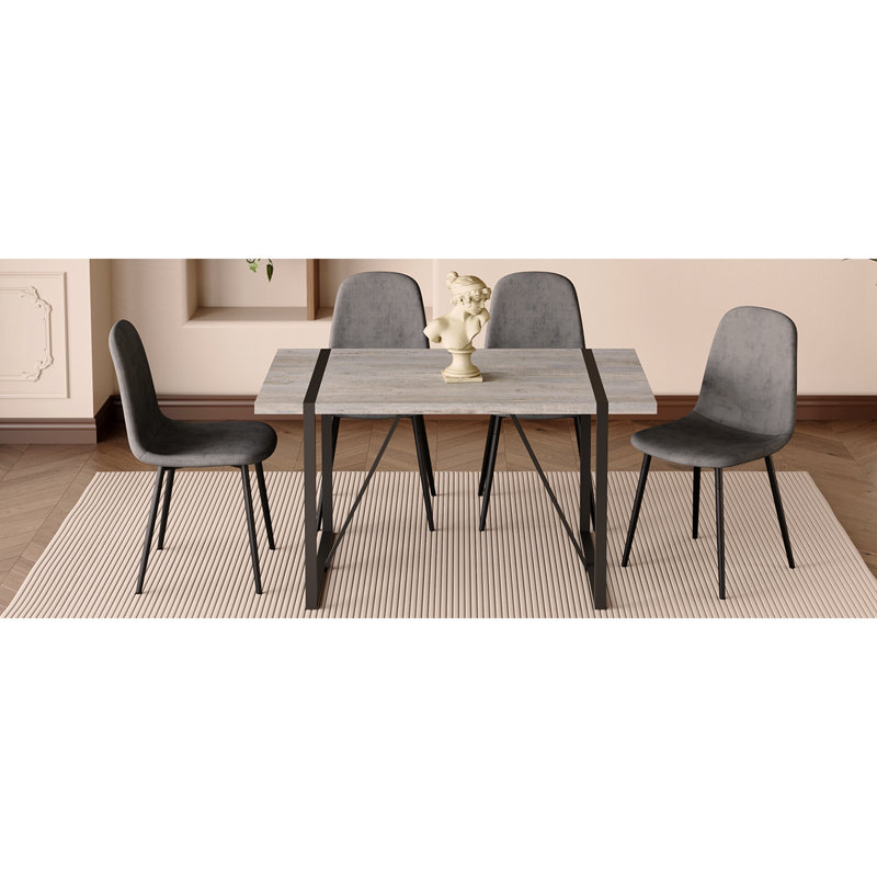 Ensemble de table et de chaises. Une table de salle à manger avec des pieds en métal noir, jumelée à 4 chaises douces et des pieds en métal noir