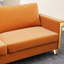 Élégant fauteuil en velours orange avec pieds en métal doré et coussins de restauration profonds