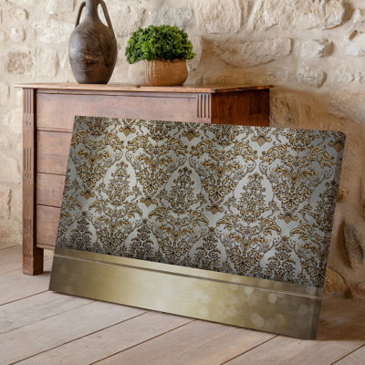 La toile crée un design de papier peint élégant avec un motif damassé complexe en or chatoyant contre un taupe doux