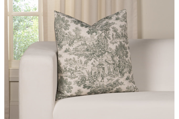 Green and ivory toilet patterned throw pillow on an ivory colored sofa in a living room