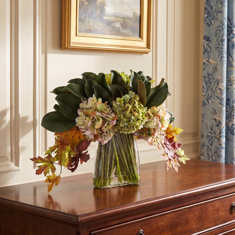 Arrangement d'automne hortensias et feuilles de magnolia dans un vase en verre