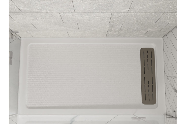 An image looking down at a rectangular white shower pan installed in a shower enclosure with white marble tile.