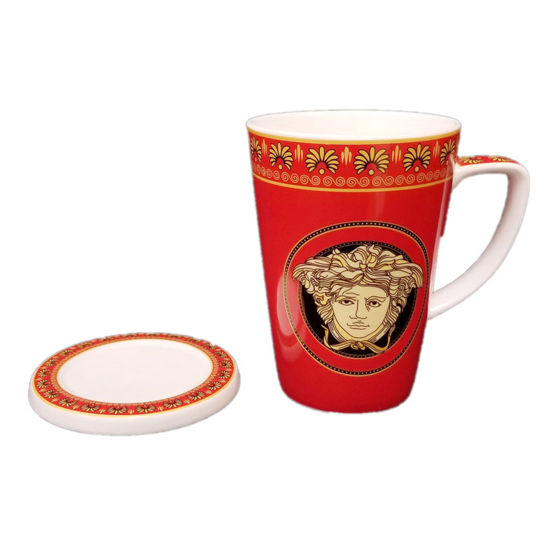 Tasse à couvercle rouge avec des accents dorés et un motif de visage
