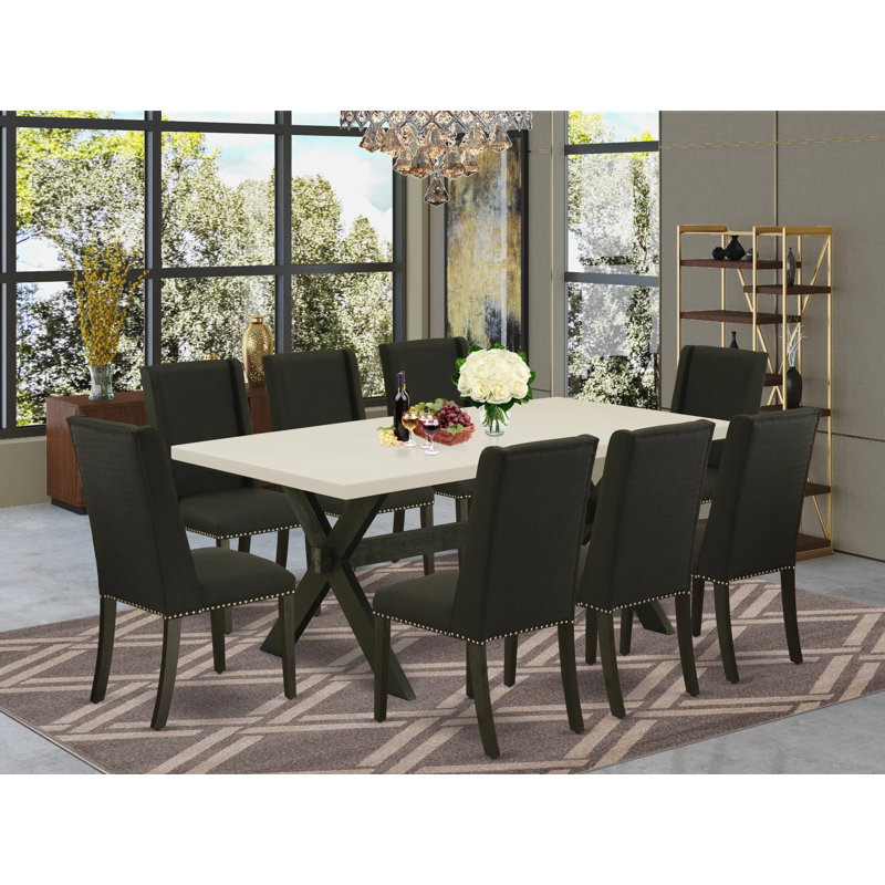 L'ensemble de mobilier de salle à manger 9 pièces comprend une table de salle à manger rectangulaire avec des pieds en X et 8 chaises Parson rembourrées en tissu noir, noir brossé