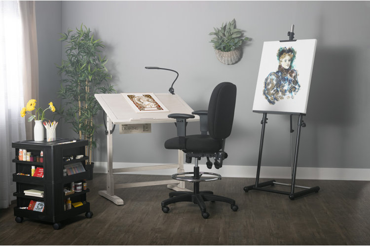 Room with a white drafting table beside a black rolling draft chair and paired with a craft cart and an art easel.