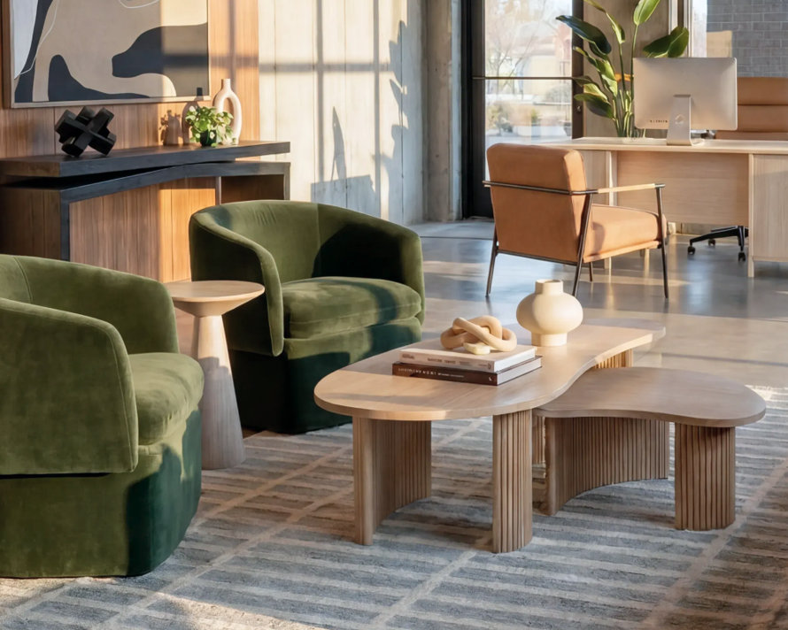 Contemporary multifamily lounge with green velvet armchairs and light wood coffee tables
