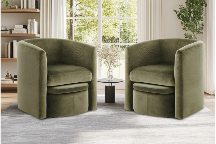 Modern olive-green velvet accent chairs with curved barrel backs, paired beside a small round side table in a bright, minimalist living room