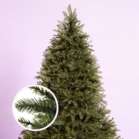 Full artificial Christmas tree against a light purple background with a circular inset highlighting the realistic detail of the green pine needles.