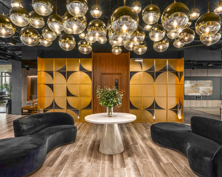 Modern multifamily lobby with a cluster of gold globe pendant lights and black curved sofas