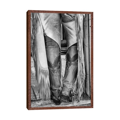 Horse Drive In Winter On Hideout Ranch, Shell, Wyoming. Cowgirl Detail Of Boots And Chaps In Doorway Of Log Cabin. by Darrell Gulin - Print on Canvas