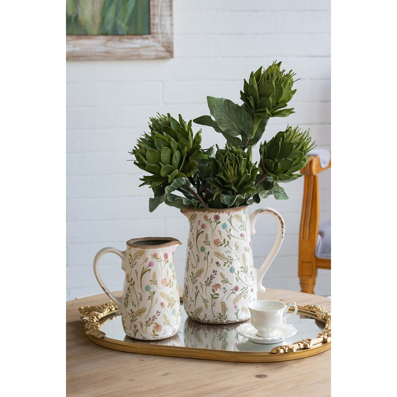 Vase rond en céramique avec des motifs floraux multicolores, une texture fabriquée à la main, une finition blanche patinée et une fonction décorative polyvalente.