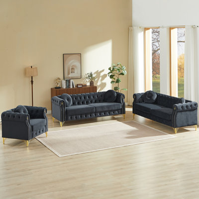 Velvet Chesterfield sofa with two round pillows, featuring copper stud detailing and tufted button accents, with metal legs. Loop design allows for hanging cartoon ornaments.