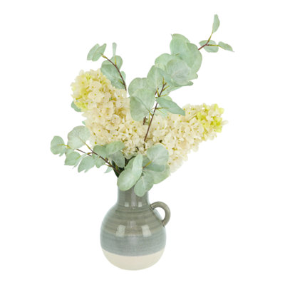 Hortensias et eucalyptus disposés dans un vase en céramique